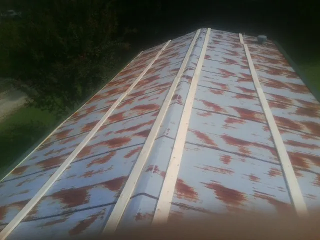 Rusted metal roof panels with new wood purlins before replacement in Union Mills