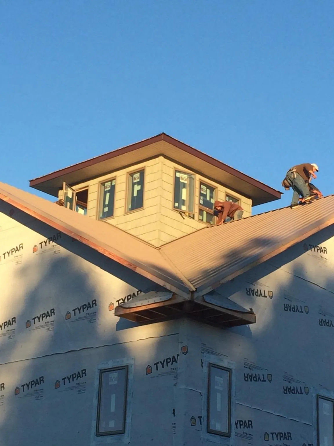 Roofers working around a rooftop cupola on a new metal roof at sunset — Roof Waterproofing in Union Mills by Roofing Brothers